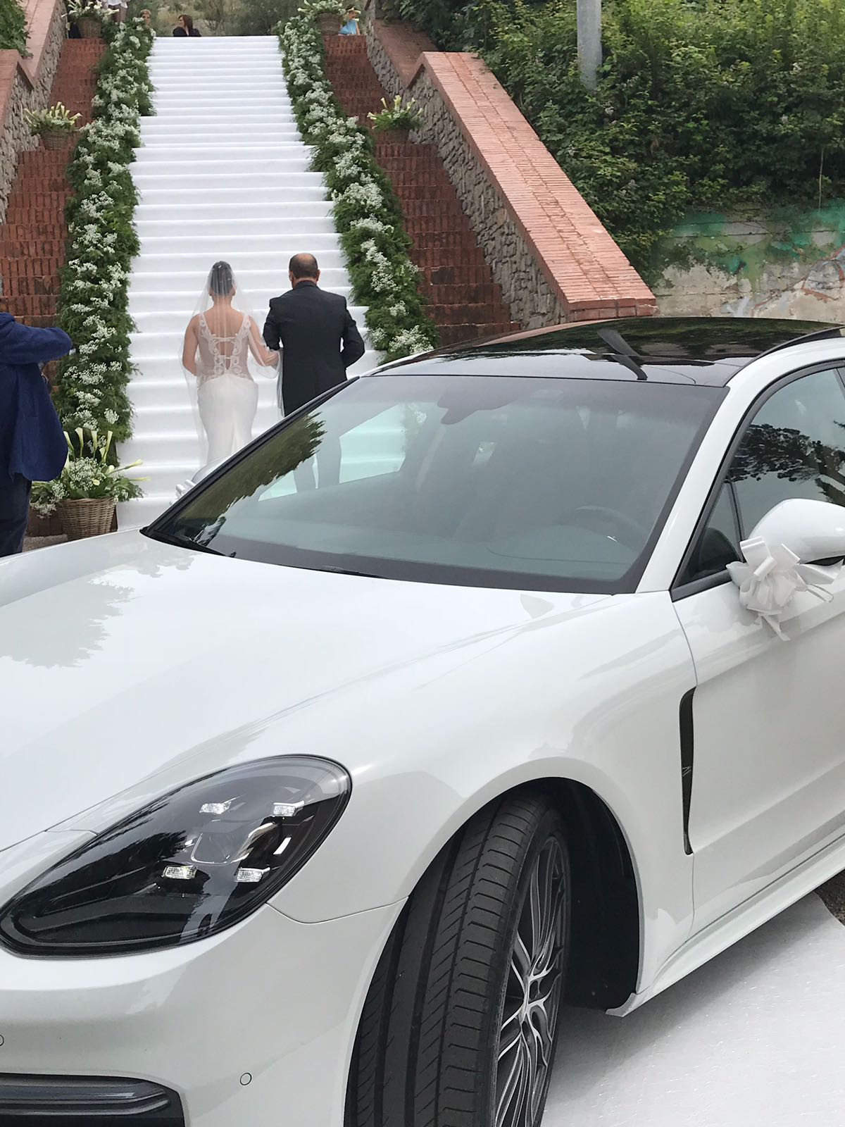 Bellissimo momento ripreso con una magnifica foto che mostra un momento impeccabile: l’arrivo in chiesa di una sposa con il papà. Una scala lunghissima con un tappeto bianco e una corona di giorni nei lati, la nostra auto che fa da cornice questo bellissimo momento...
